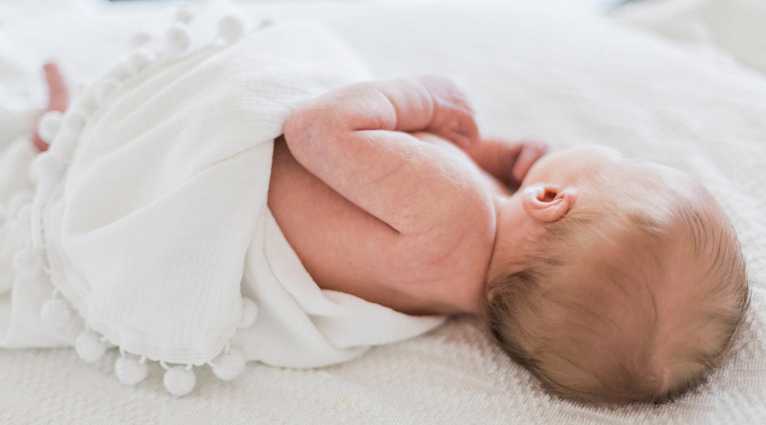 Infant sleeping in white blankets