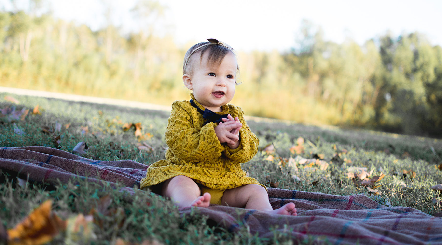 Baby girl sitting on a picnic blanket outdoors