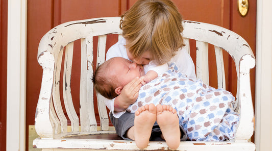 Older brother kissing newborn sibling