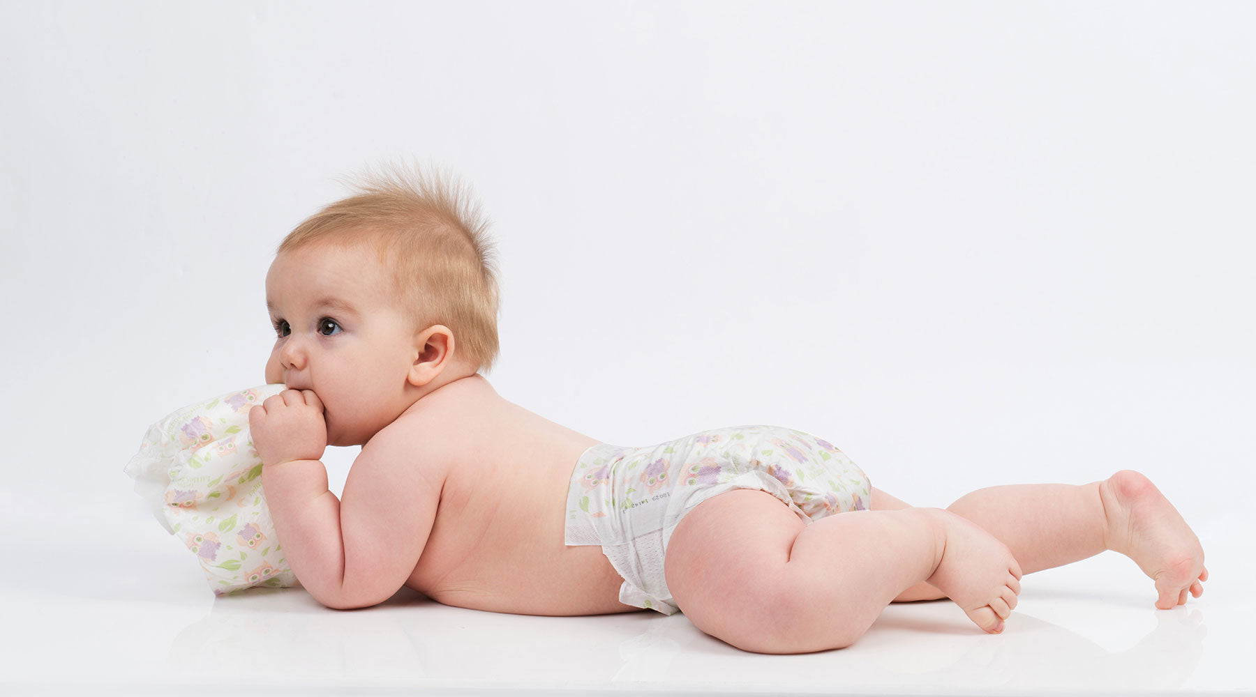 Baby laying on stomach with Happy Little Camper Diapers